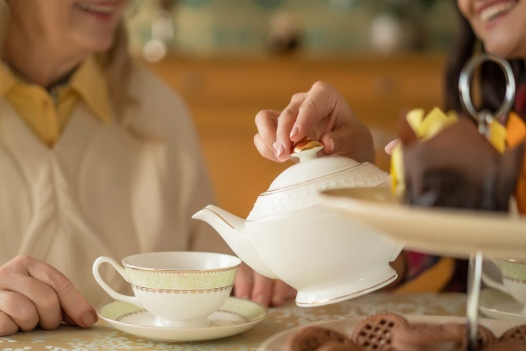 Two women talking whilst pouring a cup of tea,