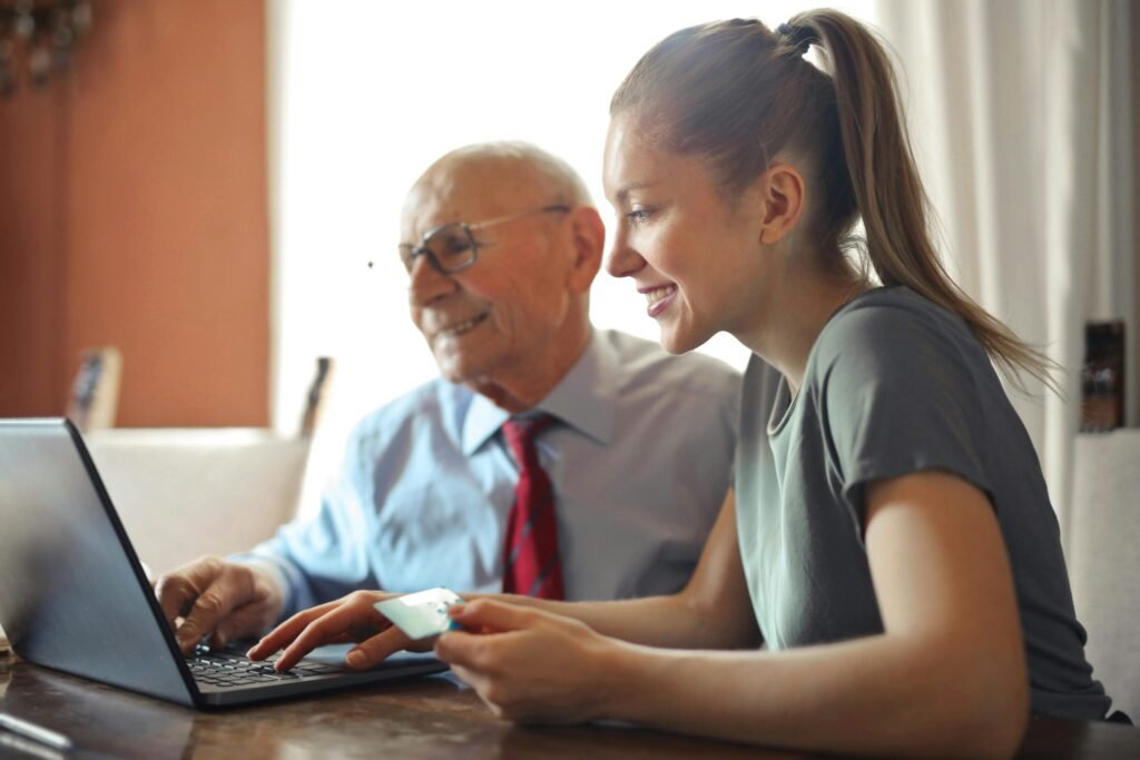 Elderly with person at laptop