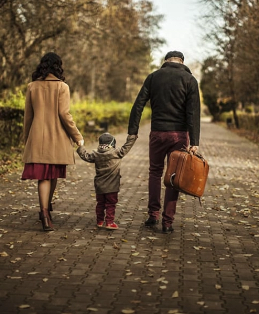 A family of three walking down the cobbled street holding hands.