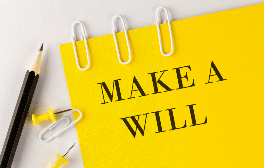 A notepad that reads 'Make a Will'. It is surrounded by clips, pins, and a pencil.
