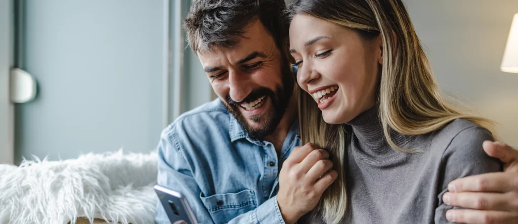 A couple happy about something on their phone.